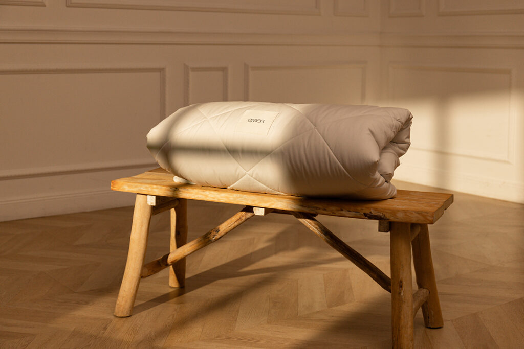 Couette de la marque Eraen 100% alapaga pliée sur un banc en bois